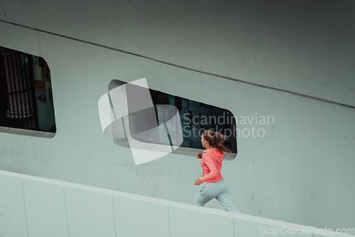 Image of Women in sports clothes running in a modern urban environment. The concept of a sporty and healthy lifestyle