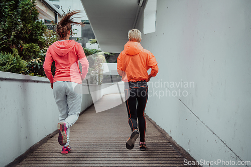 Image of Two women in sports clothes running in a modern urban environment. The concept of a sporty and healthy lifestyle