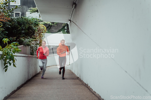 Image of Two women in sports clothes running in a modern urban environment. The concept of a sporty and healthy lifestyle