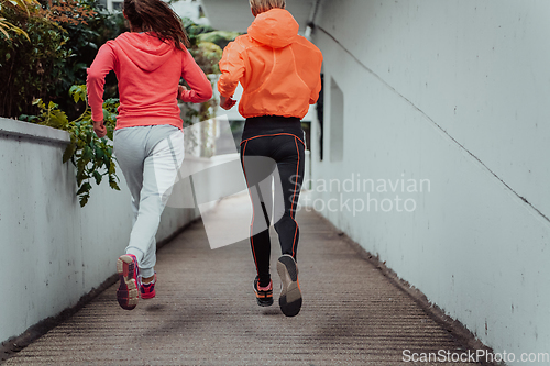 Image of Two women in sports clothes running in a modern urban environment. The concept of a sporty and healthy lifestyle