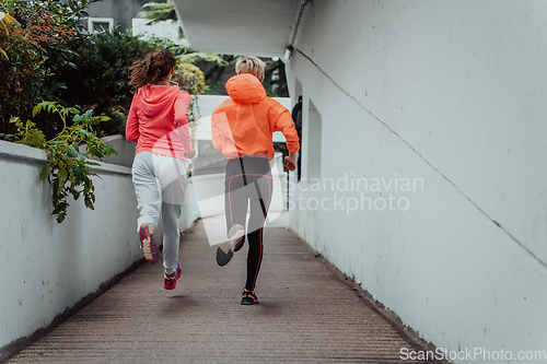 Image of Two women in sports clothes running in a modern urban environment. The concept of a sporty and healthy lifestyle