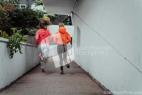 Image of Two women in sports clothes running in a modern urban environment. The concept of a sporty and healthy lifestyle