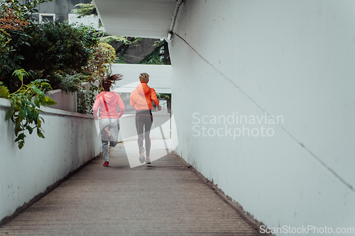 Image of Two women in sports clothes running in a modern urban environment. The concept of a sporty and healthy lifestyle