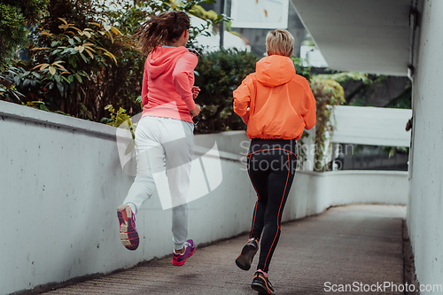 Image of Two women in sports clothes running in a modern urban environment. The concept of a sporty and healthy lifestyle