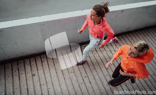 Image of Two women in sports clothes running in a modern urban environment. The concept of a sporty and healthy lifestyle