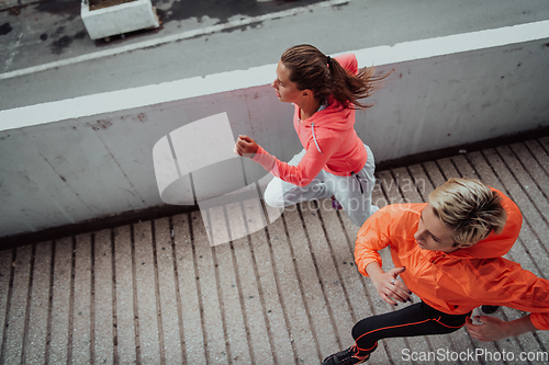 Image of Two women in sports clothes running in a modern urban environment. The concept of a sporty and healthy lifestyle