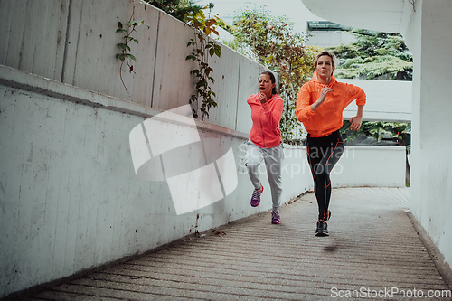 Image of Two women in sports clothes running in a modern urban environment. The concept of a sporty and healthy lifestyle