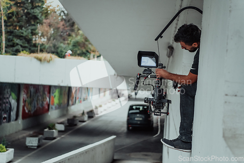 Image of A professional cameraman with equipment and a stabilizer recoding two woman for a commercial advertisement as they run in an urban environment