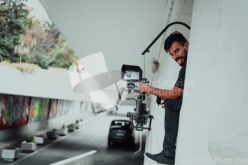 Image of A professional cameraman with equipment and a stabilizer recoding two woman for a commercial advertisement as they run in an urban environment