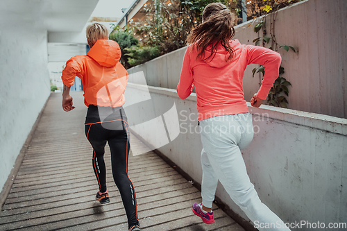 Image of Two women in sports clothes running in a modern urban environment. The concept of a sporty and healthy lifestyle