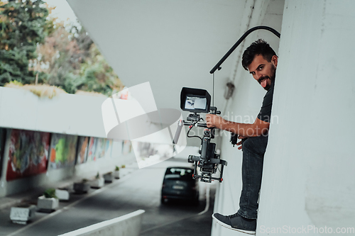 Image of A professional cameraman with equipment and a stabilizer recoding two woman for a commercial advertisement as they run in an urban environment