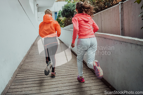 Image of Two women in sports clothes running in a modern urban environment. The concept of a sporty and healthy lifestyle