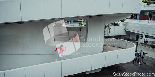 Image of Two women in sports clothes running in a modern urban environment. The concept of a sporty and healthy lifestyle