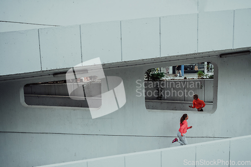 Image of Two women in sports clothes running in a modern urban environment. The concept of a sporty and healthy lifestyle