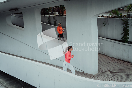 Image of Two women in sports clothes running in a modern urban environment. The concept of a sporty and healthy lifestyle