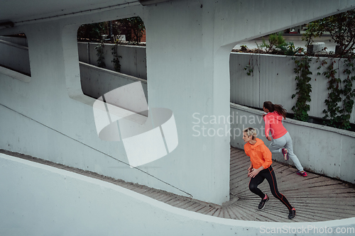 Image of Two women in sports clothes running in a modern urban environment. The concept of a sporty and healthy lifestyle