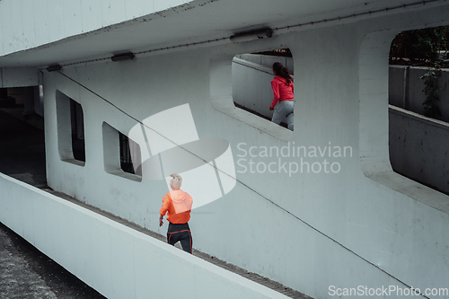 Image of Two women in sports clothes running in a modern urban environment. The concept of a sporty and healthy lifestyle