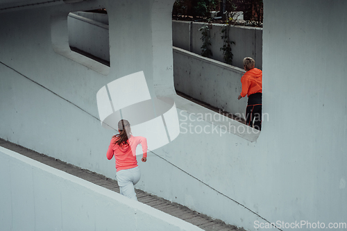 Image of Two women in sports clothes running in a modern urban environment. The concept of a sporty and healthy lifestyle