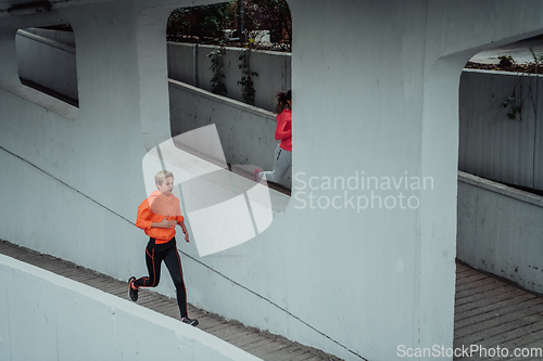 Image of Two women in sports clothes running in a modern urban environment. The concept of a sporty and healthy lifestyle