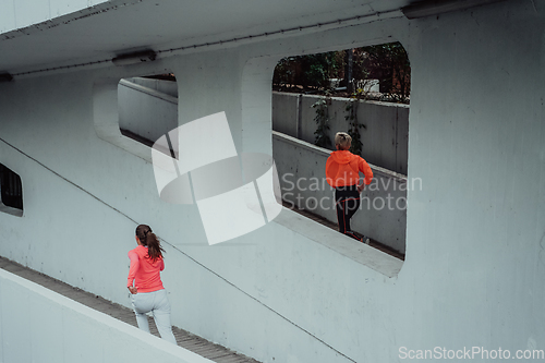 Image of Two women in sports clothes running in a modern urban environment. The concept of a sporty and healthy lifestyle