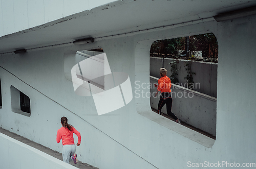 Image of Two women in sports clothes running in a modern urban environment. The concept of a sporty and healthy lifestyle