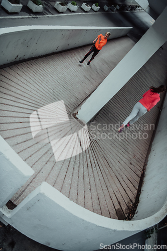 Image of Two women in sports clothes running in a modern urban environment. The concept of a sporty and healthy lifestyle