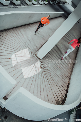 Image of Two women in sports clothes running in a modern urban environment. The concept of a sporty and healthy lifestyle