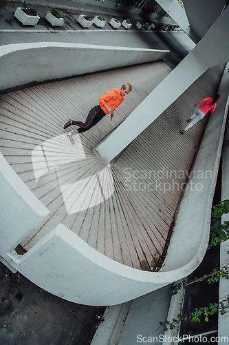 Image of Two women in sports clothes running in a modern urban environment. The concept of a sporty and healthy lifestyle