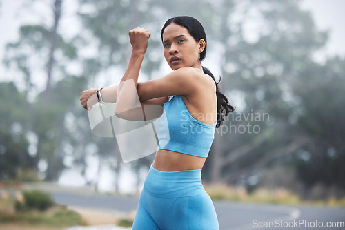 Image of Arm stretching, woman focus and runner exercise on a outdoor road in the mountains in morning. Workout, running training and wellness of a young female ready for sports and marathon run in mist