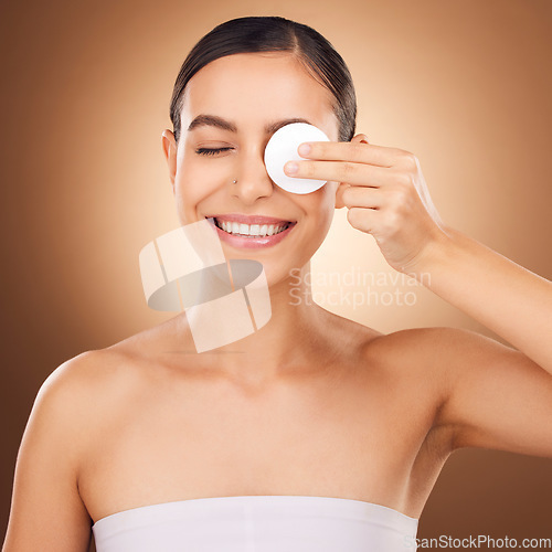 Image of Skincare, cotton pad and woman eye cleaning of a young person with happiness in a studio. Happy smile and dermatology treatment of a female wiping off cosmetics, wellness and self care facial