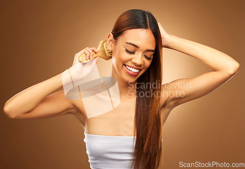 Image of Brushing hair, beauty and a happy woman in studio for growth, color shine or healthy brunette texture. Female smile for haircare brush, natural self care and hairdresser or salon on brown background