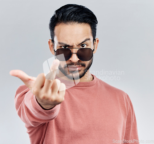 Image of Hand, middle finger and portrait of man in studio with sunglasses, attitude and gesture against grey background. Face, rebel and emoji by asian male edgy, expression and personality while isolated