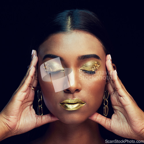 Image of Woman, face and gold makeup, beauty and glamour with eyeshadow and lipstick on black background. Indian female eyes closed, cosmetics and shimmer with facial, elegant with hands and art in studio