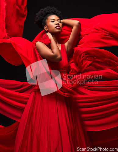 Image of Beauty, black woman and art in fashion, fabric on dark background and motion in aesthetic movement. Flowing silk, fantasy and artistic, sensual African model in red creative designer dress in studio.