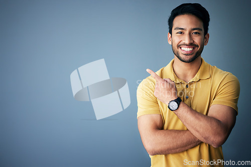 Image of Studio mockup, portrait and happy man pointing at promotion announcement, branding copy space or advertising. Smile, happiness and commercial person gesture at marketing mock up on blue background