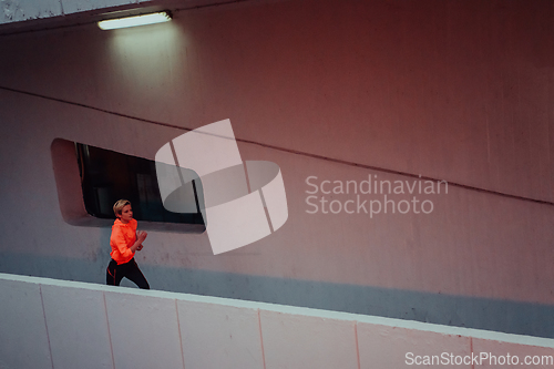 Image of Women in sports clothes running in a modern urban environment et night time. The concept of a sporty and healthy lifestyle