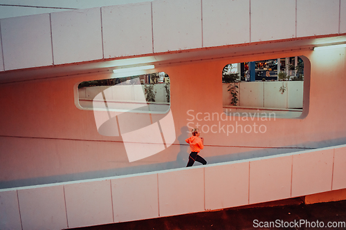 Image of Women in sports clothes running in a modern urban environment et night time. The concept of a sporty and healthy lifestyle