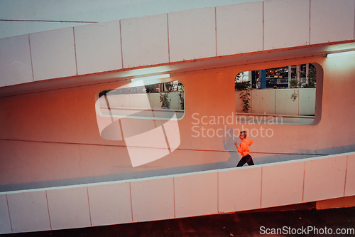 Image of Women in sports clothes running in a modern urban environment et night time. The concept of a sporty and healthy lifestyle