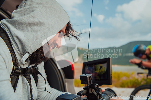 Image of A cameraman with professional equipment and camera stabilization films a triathlete on the move riding a bicycle