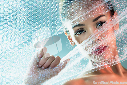 Image of Bubble wrap, beauty and portrait of woman with makeup, cosmetics and skincare products in studio. Creative art, salon aesthetic and girl with face glow, lipstick and luxury style with plastic tear