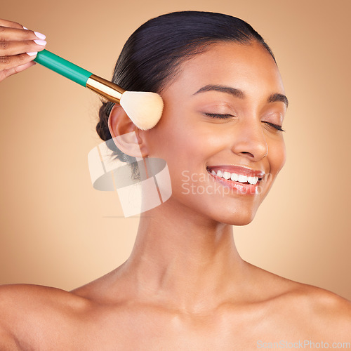 Image of Makeup, beauty and brush with indian woman in studio for foundation, blush and self care. Glow, cosmetics and facial with female model isolated on brown background for shine, blusher and application