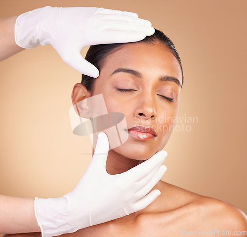 Image of Beauty, plastic surgery and hands with face of Indian woman in studio for cosmetics and skincare. Spa treatment, dermatology and anti aging with female on brown background for cosmetology results