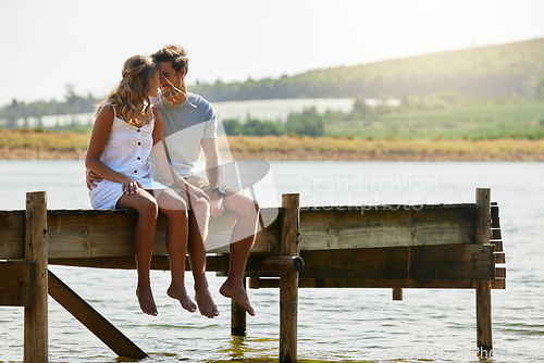 Image of Couple sitting on jetty, relax by lake and summer, travel and adventure, love and care outdoor. People in relationship, trust and bonding on vacation, man and woman with freedom and forehead touch