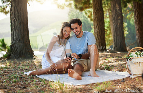 Image of Couple on picnic, phone and relax together in nature, happy people with social media, travel with bonding outdoor. Happiness, man and woman, communication with trust and love in relationship