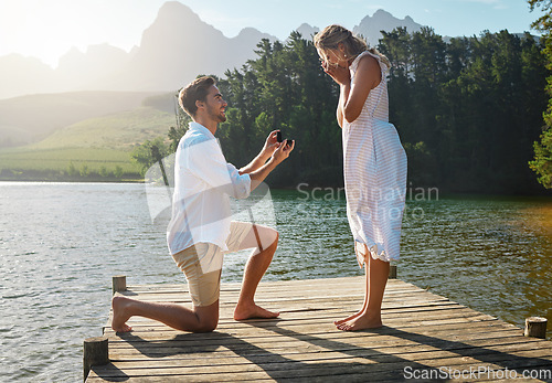 Image of Man, woman and marriage proposal by lake on vacation with surprise, wow or happiness in sunshine. Couple, engagement and offer ring in nature for romance, love and happy on holiday in summer by water