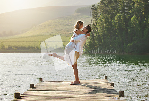 Image of Couple, lake hug and engagement announcement of young people in love in nature. Happy, relax and happiness of woman and man together by water outdoor on summer vacation by a lakeside on holiday break