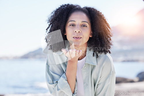 Image of Woman at beach, portrait and blow kiss, love and freedom with travel, positive gesture and peace. Calm, happy and female person outdoor, young and carefree with emoji, care and romance with adventure