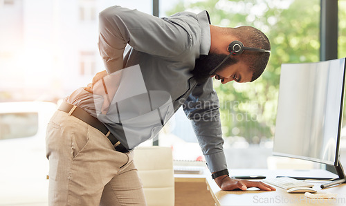Image of Call center, back pain and a black man consultant in his office, standing while holding is spine. Injury, customer service or support and a young male employee with muscle strain in a crm workplace
