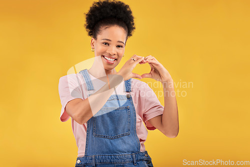 Image of Black woman, hands and sign for a heart, love and portrait of care or support on yellow background in studio. Happy, face and girl with hand gesture for loving, kindness or emoji for caring mindset