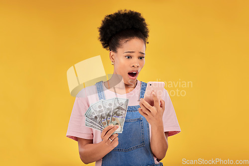 Image of Surprise, money and winner with black woman and phone in studio for success, prize or deal. Bonus, lottery and online payment with person and cash on yellow background for dollar, profit or giveaway